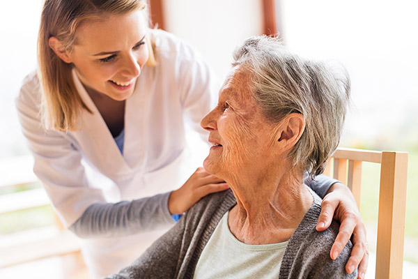 Healthcare professional speaking with senior patient in home.
